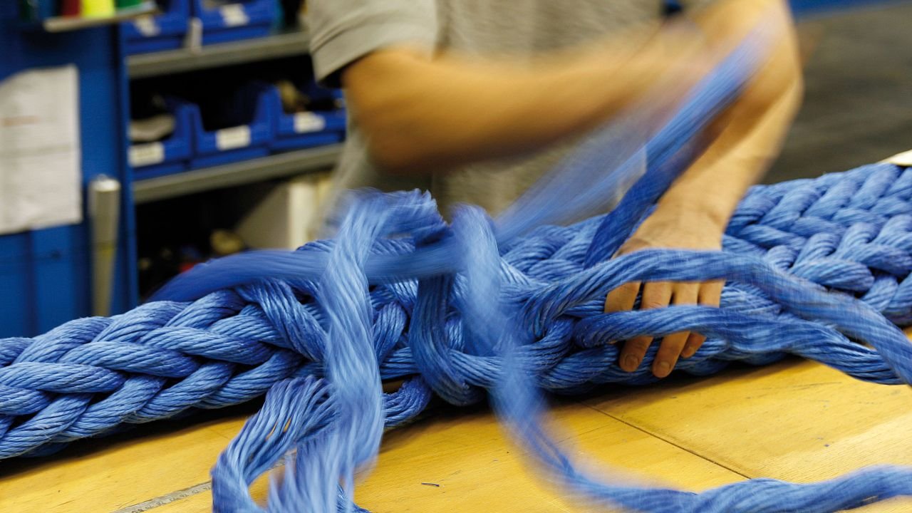 Nahaufnahme von Spleißarbeiten an einem dicken, blauen Faserseil.